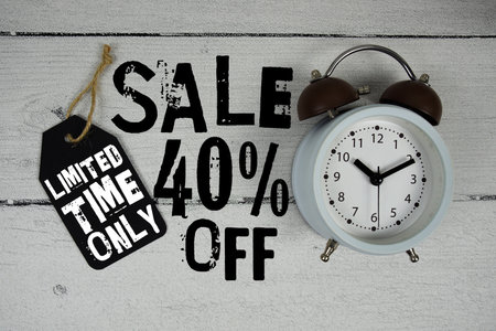 Sale 40% Off Limited Time Only with price tag and alarm clock on wooden backgroundの写真素材