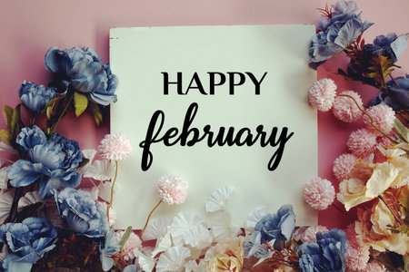 Happy February text with flowers decorations on pink backgroundの写真素材