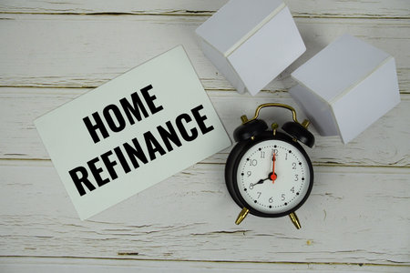 Home Refinance text message on paper card with alarm clcok and white house modelon wooden backgroundの写真素材
