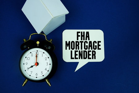 FHA Mortgage Lender text with alarm clock and house model top view on blue backgroundの写真素材