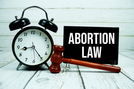 Abortion Law text on paper card with alarm clock and wooden judge gavel on wooden backgroundの写真素材