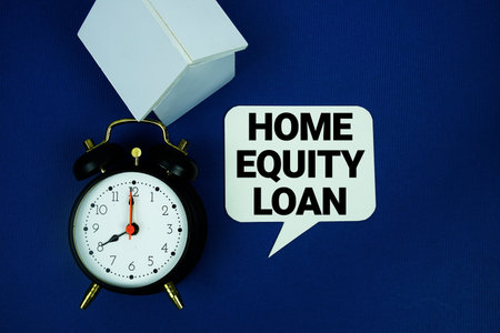 Home Equity Loan text with alarm clock and house model top view on blue backgroundの写真素材