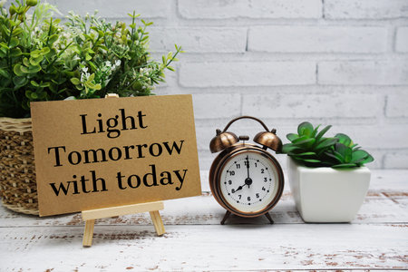 Light Tomorrow with today text message with easel stand on wooden background