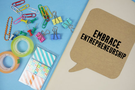 Embrace Entrepreneurship text with stationery on cover notebook background