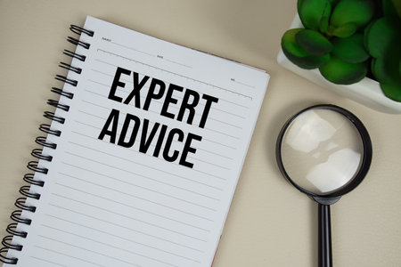 Expert Advice text on paper notebook with magnifying glass on beige leather backgroundの写真素材
