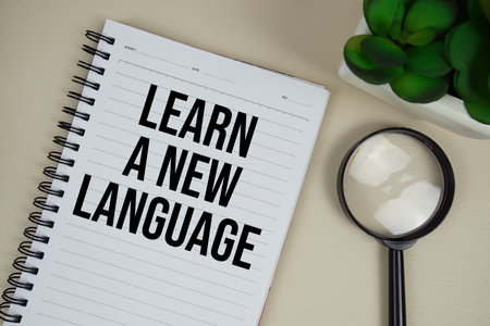 Learn A New Language text on paper notebook with magnifying glass on beige leather backgroundの写真素材