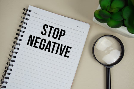 Stop Negative text on paper notebook with magnifying glass on beige leather backgroundの写真素材