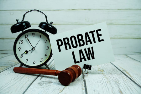Probate Law text on paper card with alarm clock and wooden judge gavel on wooden background