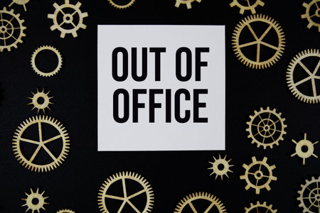 Out of Office text on paper and gear on black background