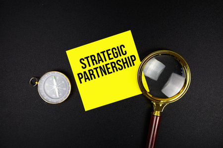 Strategic Partnershiptext message on sticky note with magnifying glass and compass on black backgroundの写真素材