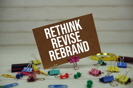 Rethink Revise Rebrand text on paper card with stationary on wooden backgroundの写真素材