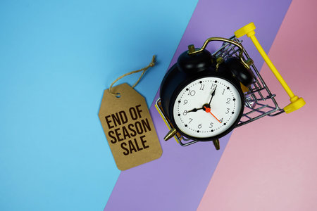End Of Season Sale 70% text on price tag with alarm clock and trolley shopping cart on pink, purple,...