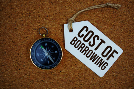 Cost Of Borrowing text on price tag with compass on cork board background