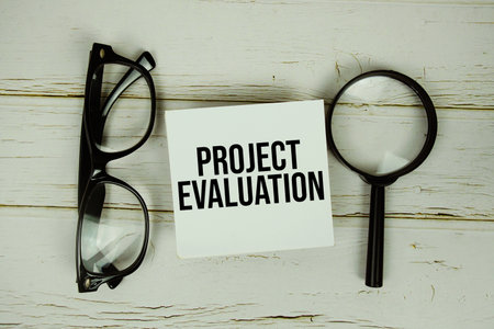Project Evaluation text message on paper with magnifying glass and eyeglasses on wooden backgroundの写真素材