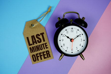 Last Minute Offer text on price tag with alarm clock and trolley shopping cart on pink, purple, blue geometric backgroundの写真素材