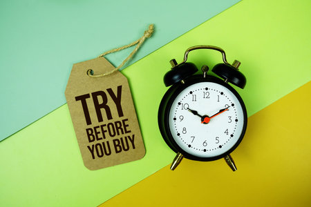 Try Before You Buy text on price tag with alarm clock on green and yellow geometric background