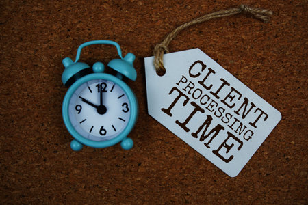 Client Processing Time text on price tag with alarm clock on cork board backgroundの写真素材