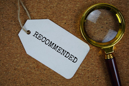 Recommended text on price tag with magnifying glass on cork board backgroundの写真素材