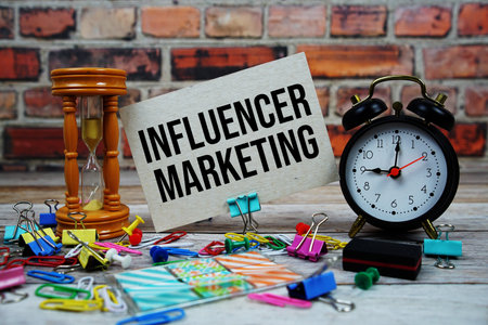 Influencer Marketing text on paper card with alarm clock and stationary on wooden backgroundの写真素材