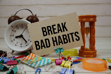 Break Bad Habits text on paper card with alarm clock and stationary on wooden backgroundの写真素材