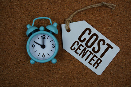 Cost Center text on price tag with alarm clock on cork board background