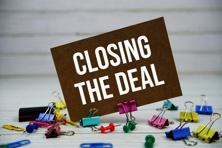 Closing The Deal text on paper card with stationary on wooden background