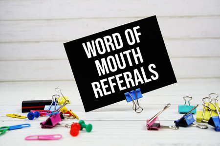 Word Of Mouth Referals text on paper card with stationary on wooden backgroundの写真素材
