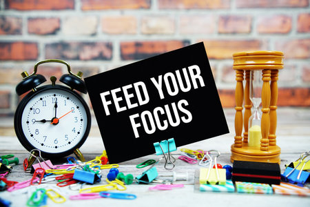 Feed Your Focus text on paper card with alarm clock and stationary on wooden backgroundの写真素材