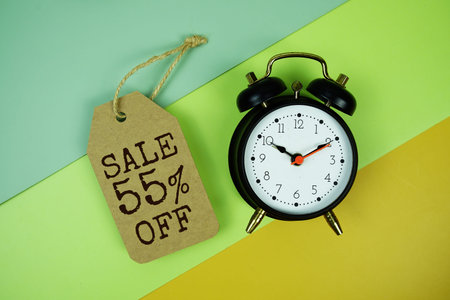 Sale 55% off text on price tag with alarm clock on green, yellow geometric background