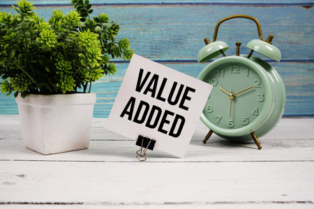 Value Added text written on paper card with alarm clock on wooden backgroundの写真素材