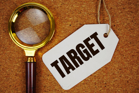 Target text on price tag with magnifying glass on cork board backgroundの写真素材
