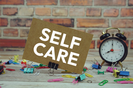 Self Care text on paper card with alarm clock and stationary on wooden backgroundの写真素材