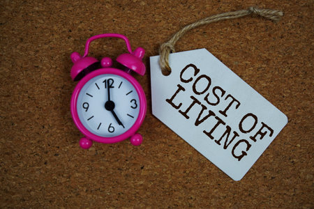 Cost Of Living text on price tag with alarm clock on cork board backgroundの写真素材