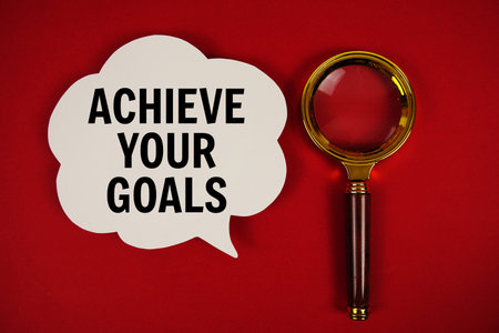 Achieve Your Goals text with speech bubble and magnifying glass on red backgroundの写真素材