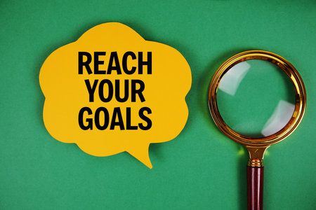 Reach Your Goals text with speech bubble and magnifying glass on green backgroundの写真素材