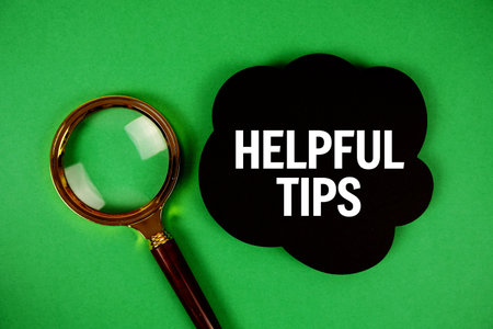 Helpful Tips text with speech bubble and magnifying glass on green backgroundの写真素材