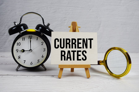 Current Rates Text With Easel And Alarm Clock On Wooden Backgroundの写真素材