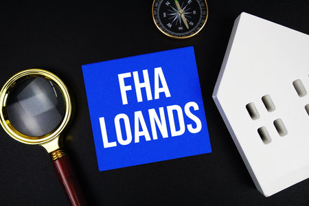 FHA LOANS text with magnifying glass, compass and house model on black backgroundの写真素材
