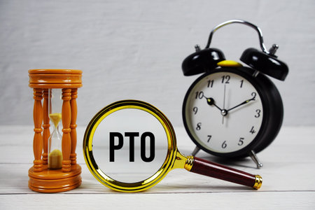 PTO abbreviation of Paid Time Off text with alarm clock on wooden backgroundの写真素材