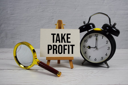 Take Profit text with alarm clcok and magnifying glass on wooden backgroundの写真素材