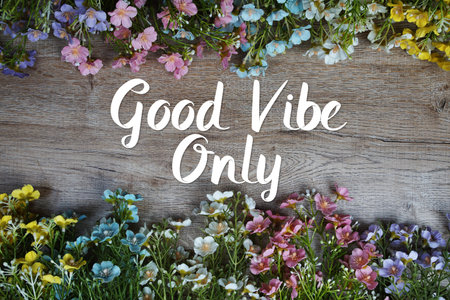 Good Vibe Only text message with flowers decoration on wooden background