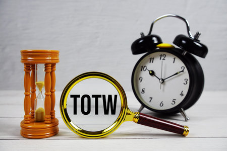 TOTW abbreviation of Time Off for Time Worked text with alarm clock on wooden background