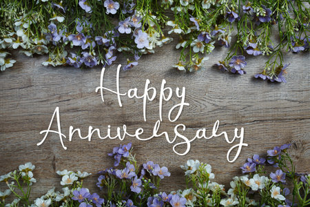 Happy Anniversary text message with flowers decoration on wooden backgroundの写真素材