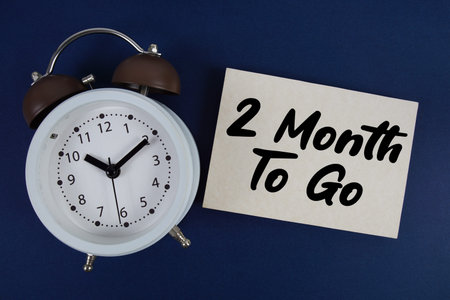 2 Month To Go text written on paper with alarm clock on blue background