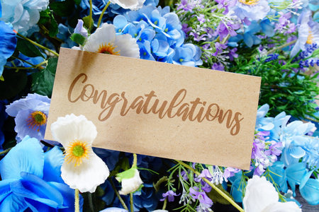Congratulations text write on paper card with flowers decoration on wooden backgroundの写真素材