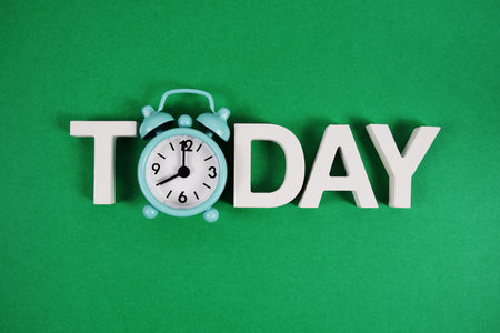 Today alphabet letters with alarm clock on green backgroundの写真素材