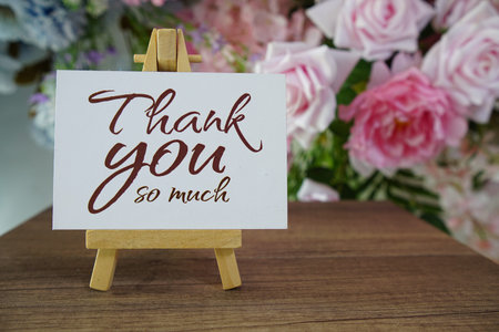 Thank you text write on paper card with wooden easel and flowers decoration on wooden background