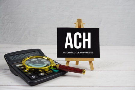 ACH Automated Clearing House text with magnifying glass and calculator on wooden backgroundの写真素材