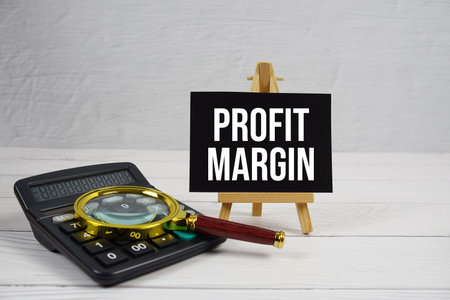 Profit Margin text with magnifying glass and calculator on wooden backgroundの写真素材