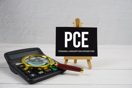 PCE abbreviation of Personal Consumption Expenditure text with magnifying glass and calculator on wooden backgroundの写真素材